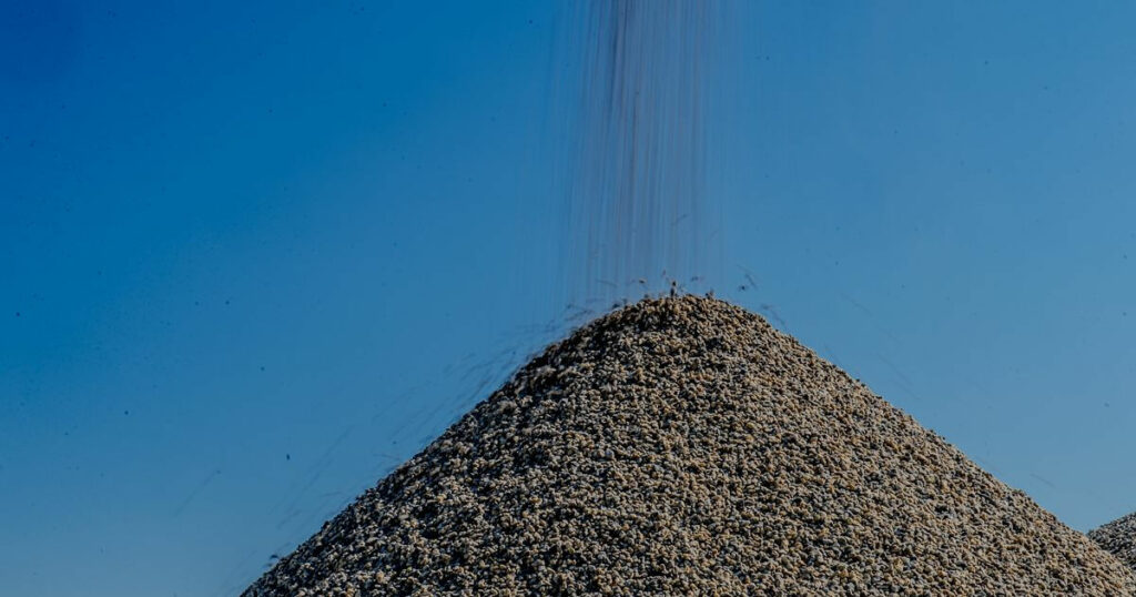 A large pile of crushed stone material being poured, showing the process of mobile crushing services.